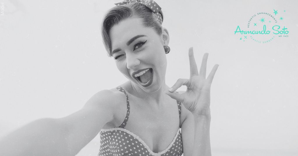 Retro-style woman with vintage makeup and hairstyle, winking and gesturing 'okay' with her hands. (MODEL)
