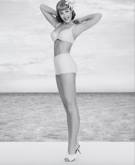 Smiling woman wearing a vintage 1960s bikini poses to the camera (MODEL) 